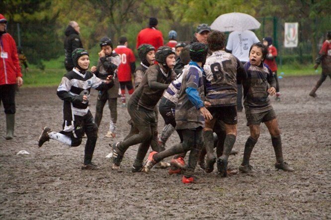 Un gruppo di ragazzi gioca a rugby nel fango.