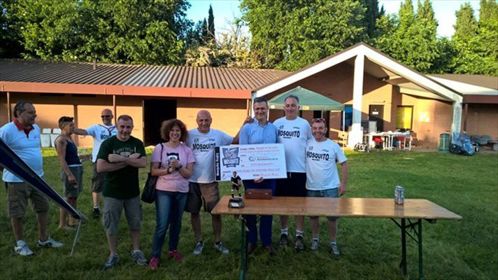 Un gruppo di persone in piedi davanti a una casa con in mano un assegno