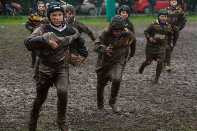 Un gruppo di ragazzi gioca a rugby nel fango.