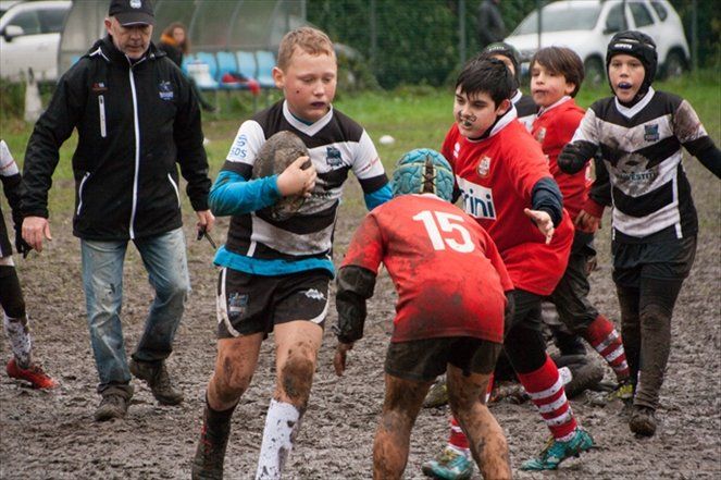Un gruppo di ragazzi gioca a rugby su un campo fangoso.