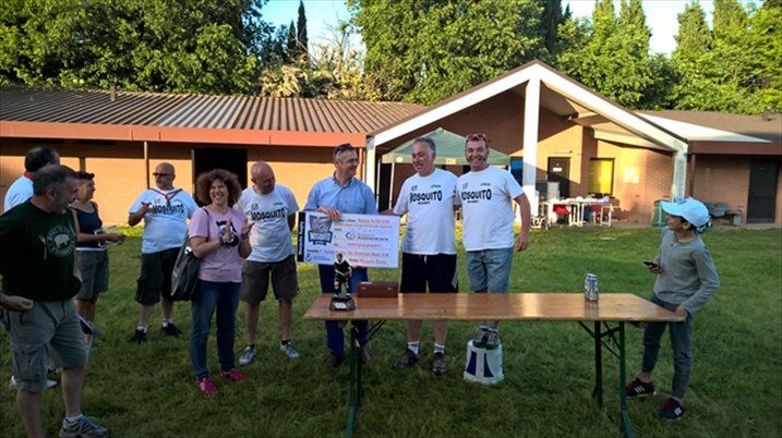 Un gruppo di persone in piedi attorno a un tavolo di fronte a un edificio.