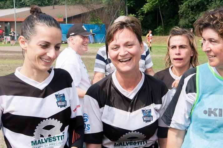 Un gruppo di donne che indossano magliette dei Malvestiti bianche e nere sono in piedi su un campo.
