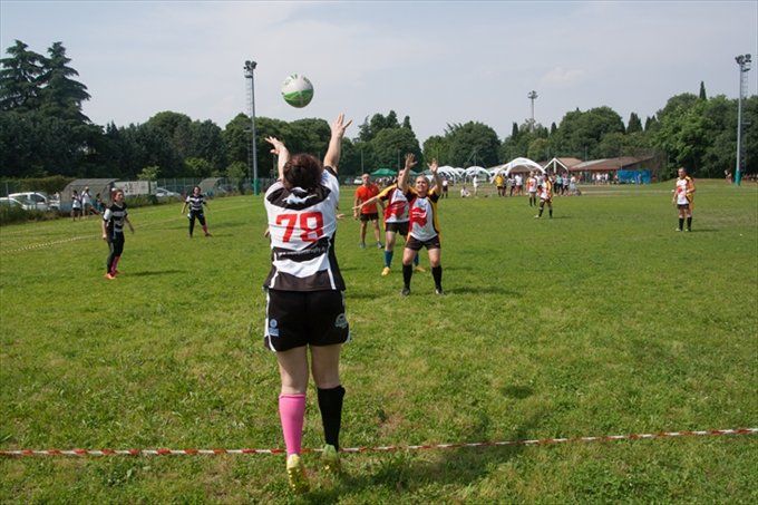 Una donna con il numero 79 sulla schiena sta lanciando una palla da rugby