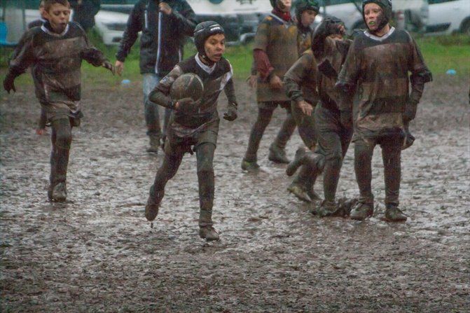 Un gruppo di ragazzi gioca a rugby nel fango.