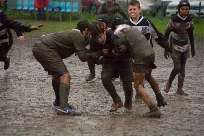 Un gruppo di giovani uomini sta giocando a rugby nel fango.