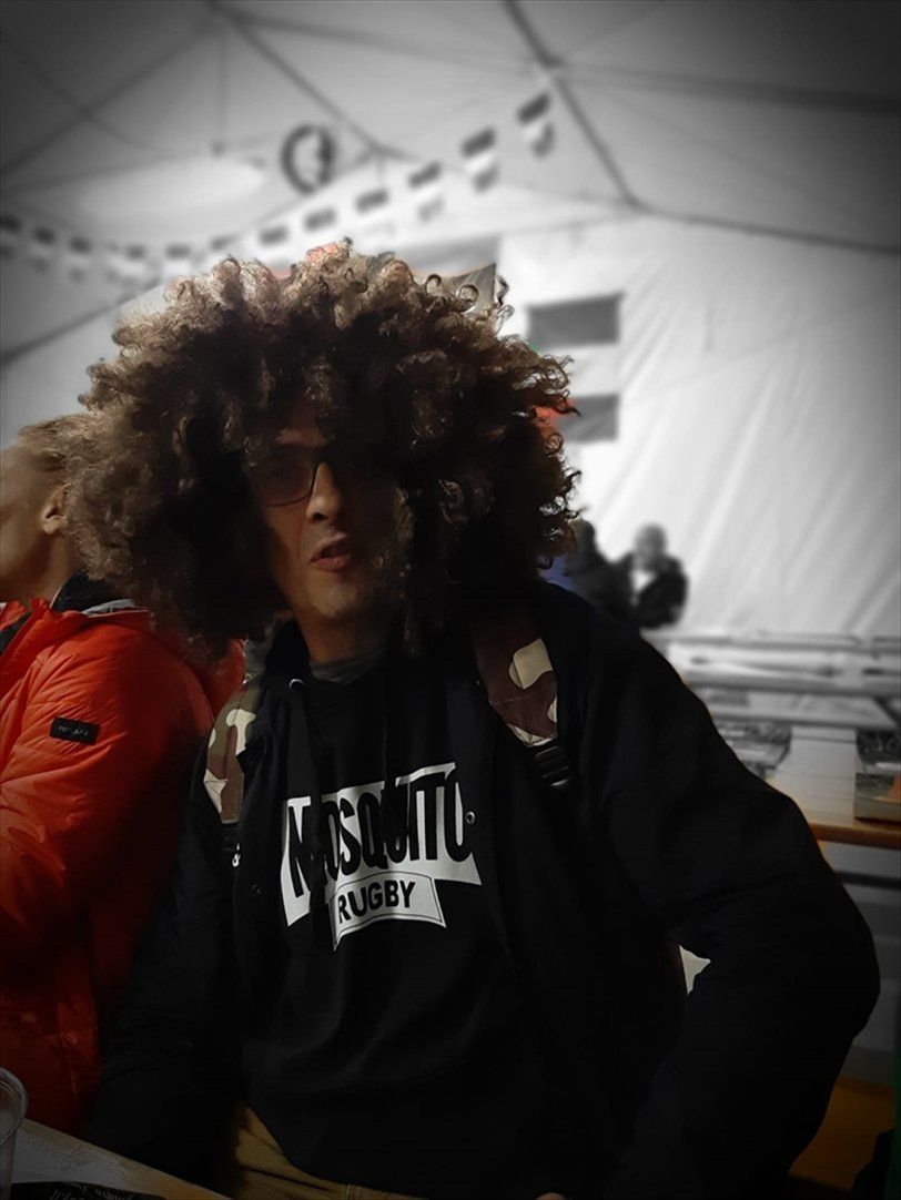 Un uomo con i capelli ricci indossa una maglietta con la scritta 