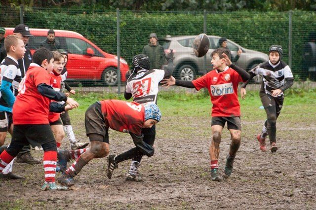 Un gruppo di ragazzi gioca a rugby su un campo fangoso.