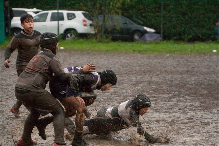 Un gruppo di ragazzi gioca a rugby nel fango.