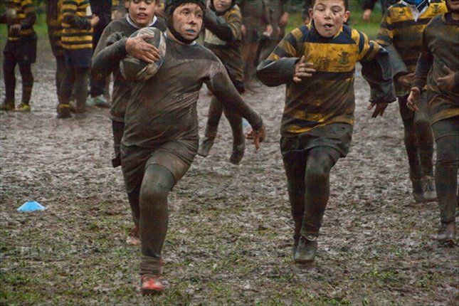 Un gruppo di ragazzi gioca a rugby nel fango.