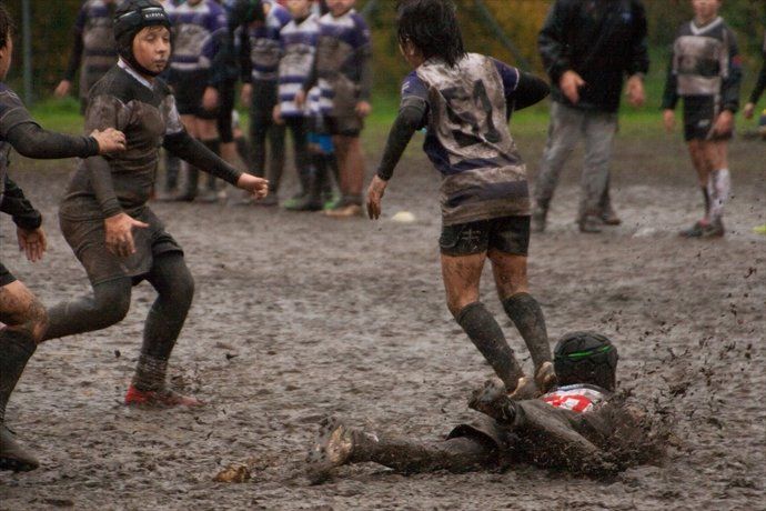 Un gruppo di bambini sta giocando a rugby nel fango.