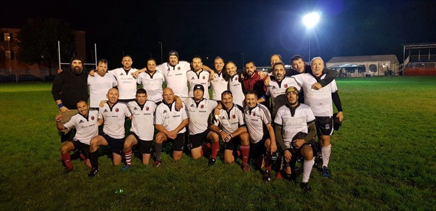 Una squadra di rugby posa per una foto su un campo di notte.