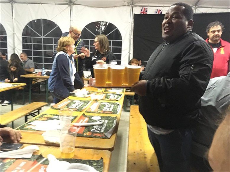 Un uomo è in piedi davanti a un tavolo pieno di boccali di birra