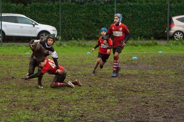 Un gruppo di ragazzi gioca a rugby su un campo fangoso.