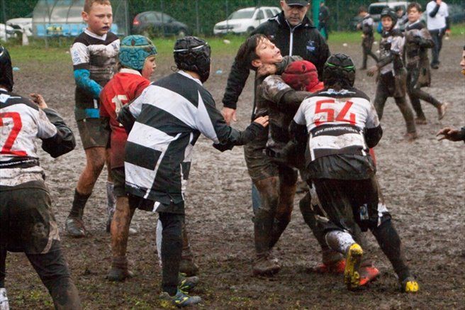 Un gruppo di ragazzi sta giocando una partita di rugby nel fango.