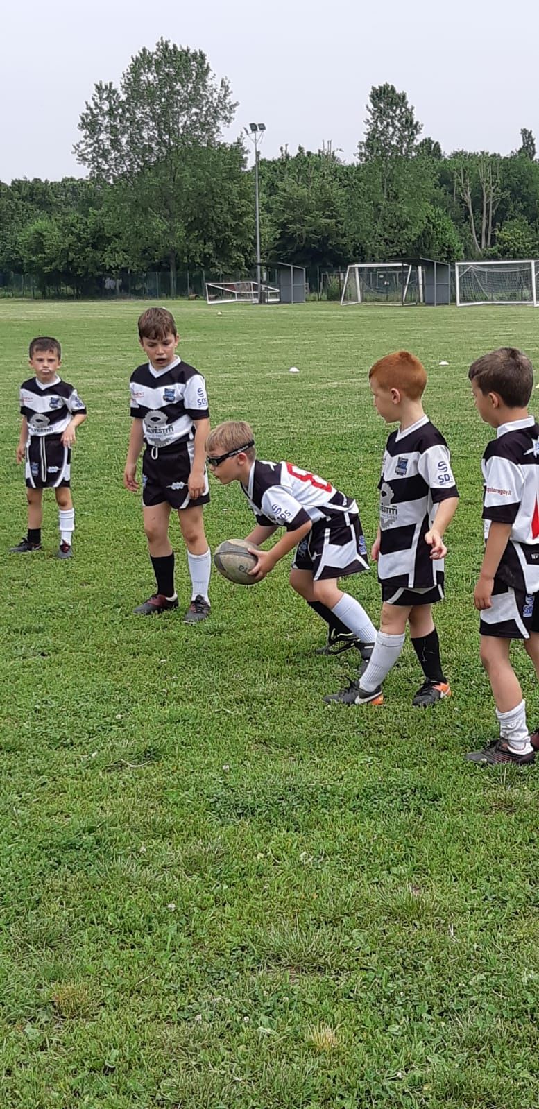 Un gruppo di ragazzi sta giocando a rugby su un campo.