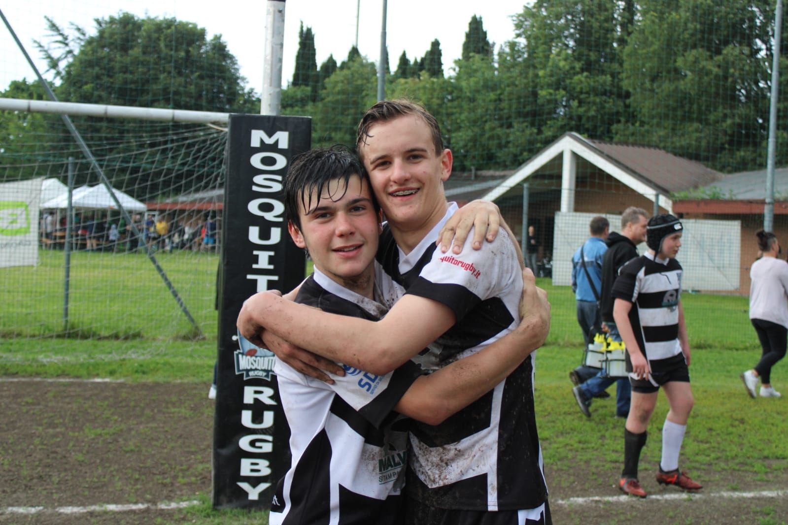 Due ragazzi che si abbracciano davanti a un cartello che dice 