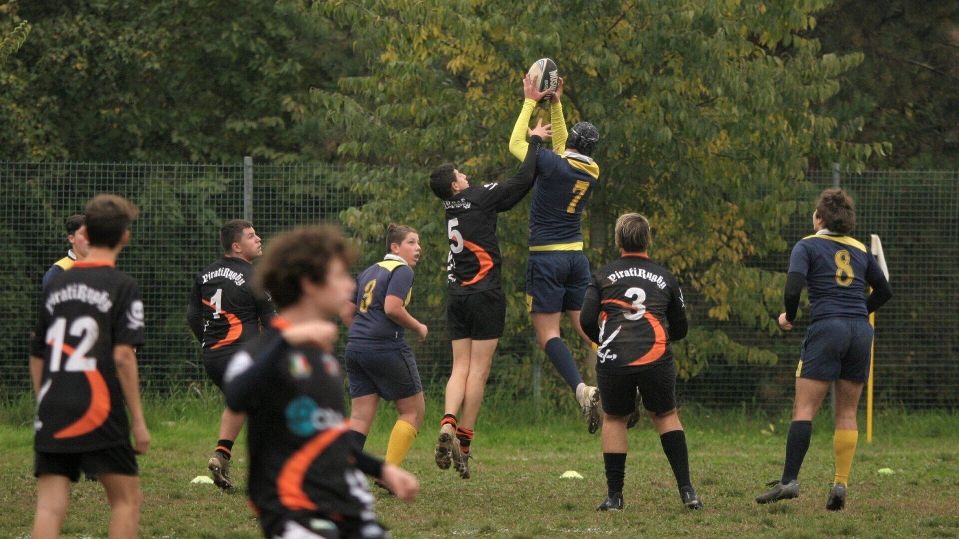 Un gruppo di giovani uomini sta giocando una partita di rugby su un campo.