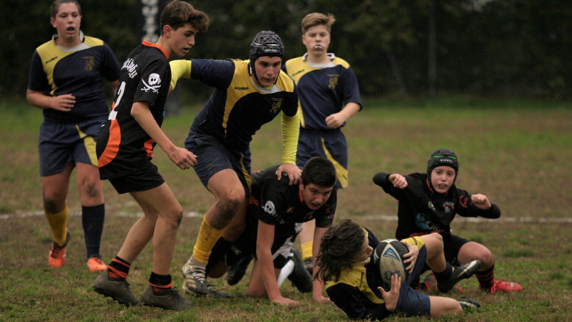 Un gruppo di ragazzi sta giocando a rugby su un campo.