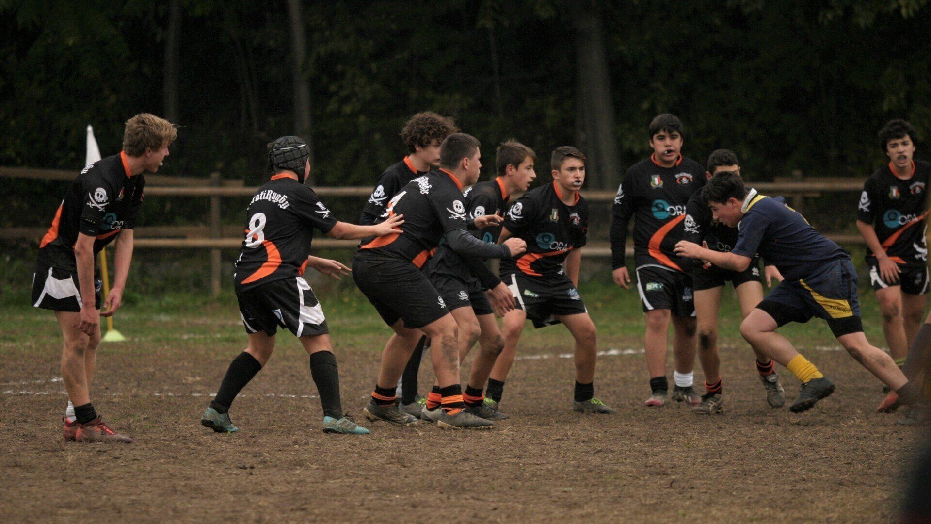 Un gruppo di giovani sta giocando una partita di rugby su un campo fangoso.