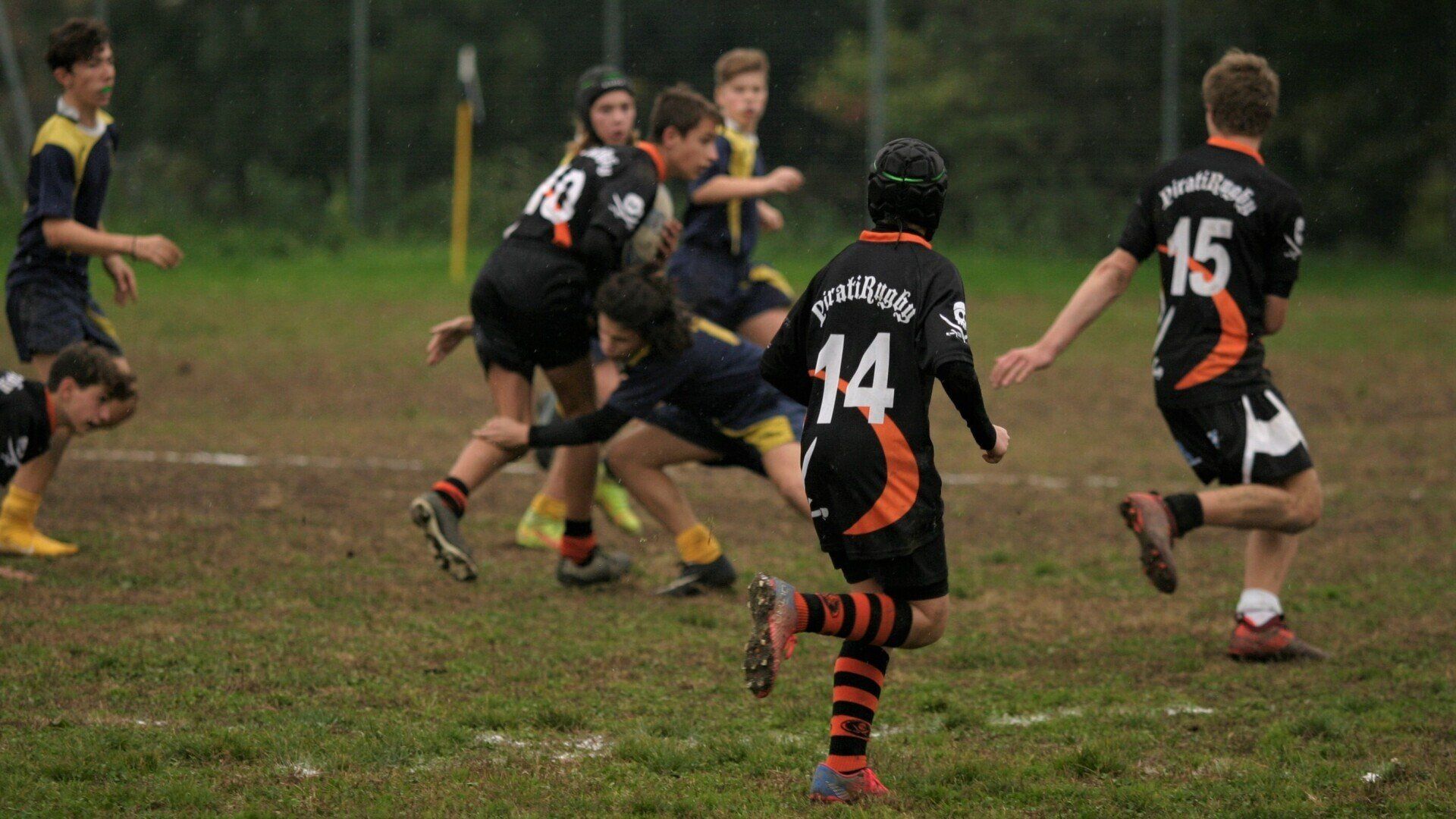 Un gruppo di ragazzi sta giocando una partita di rugby su un campo.