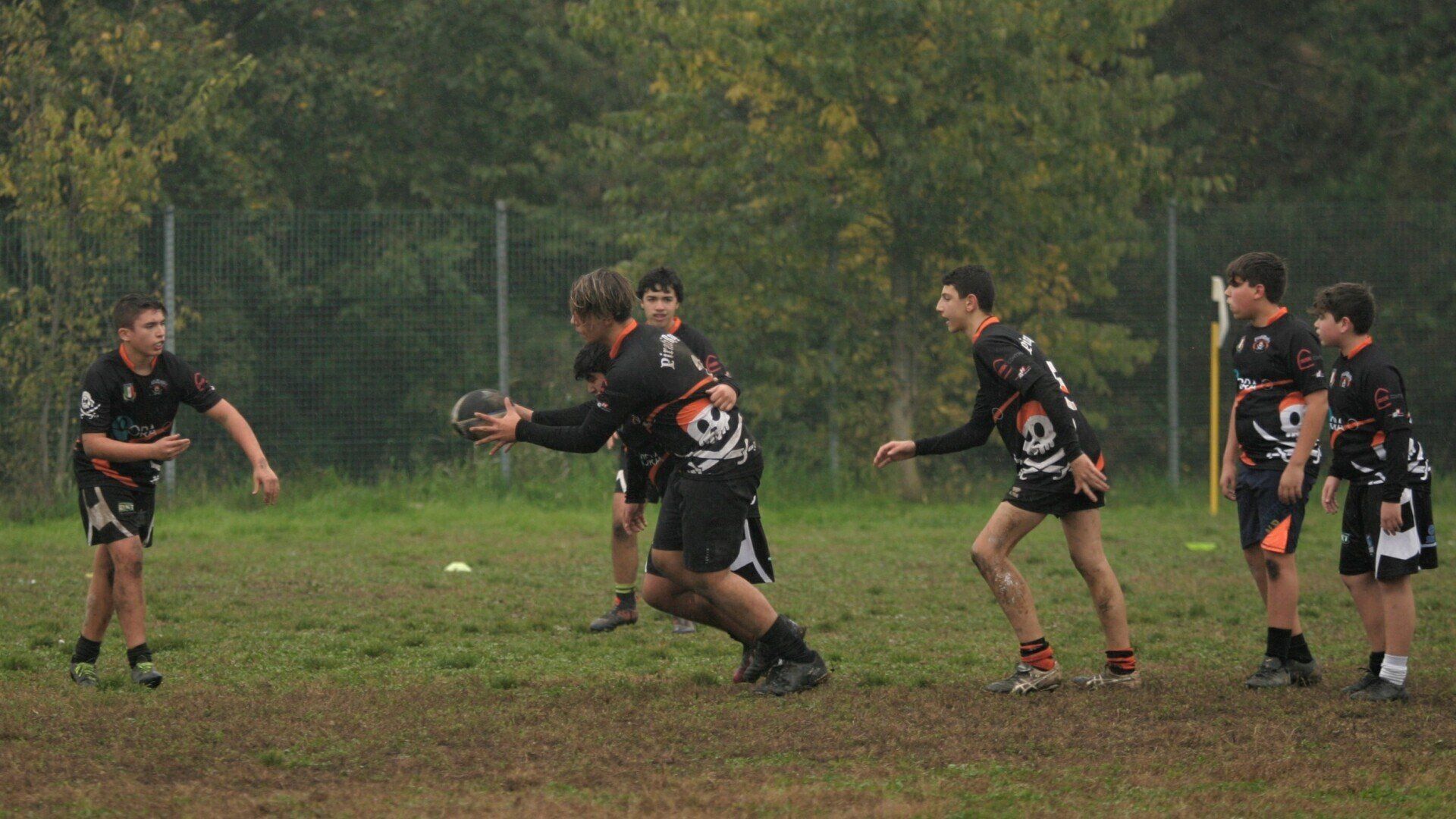 Un gruppo di ragazzi sta giocando una partita di rugby su un campo.