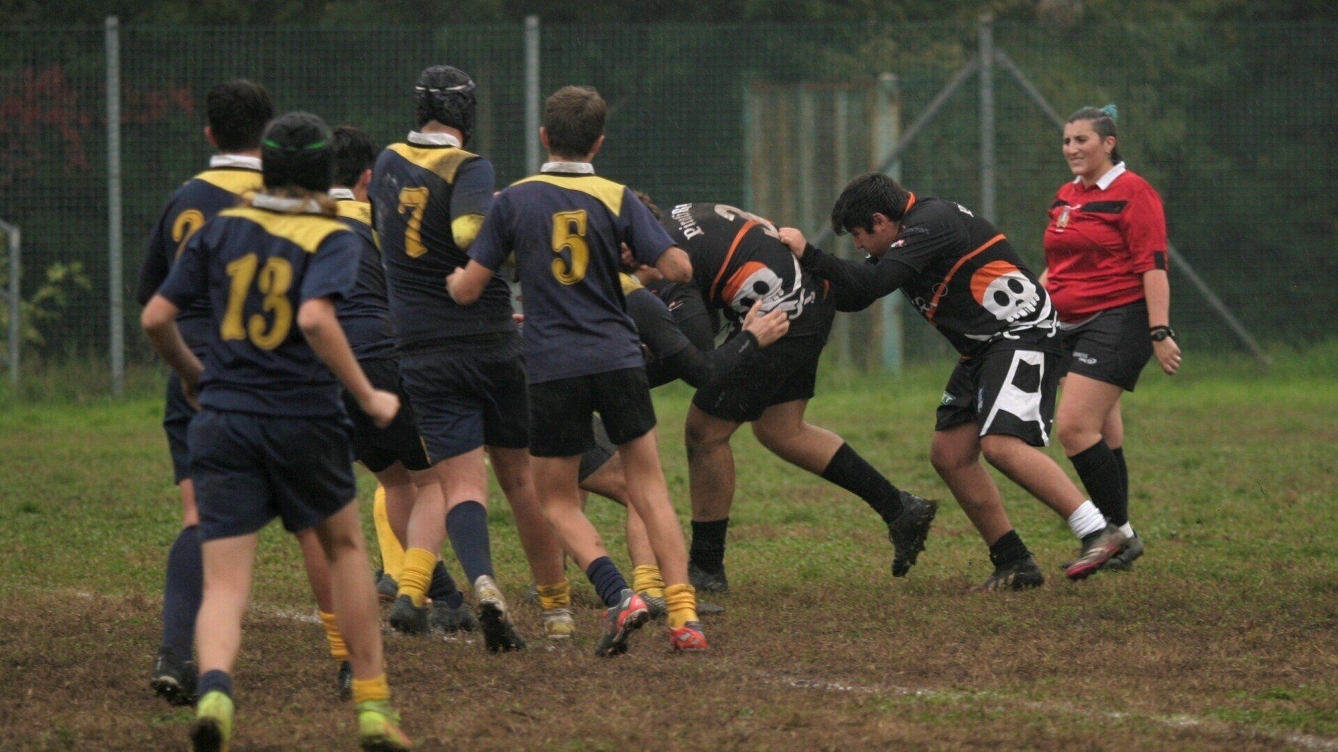 Un gruppo di giocatori di rugby sta giocando su un campo sotto gli occhi di un arbitro