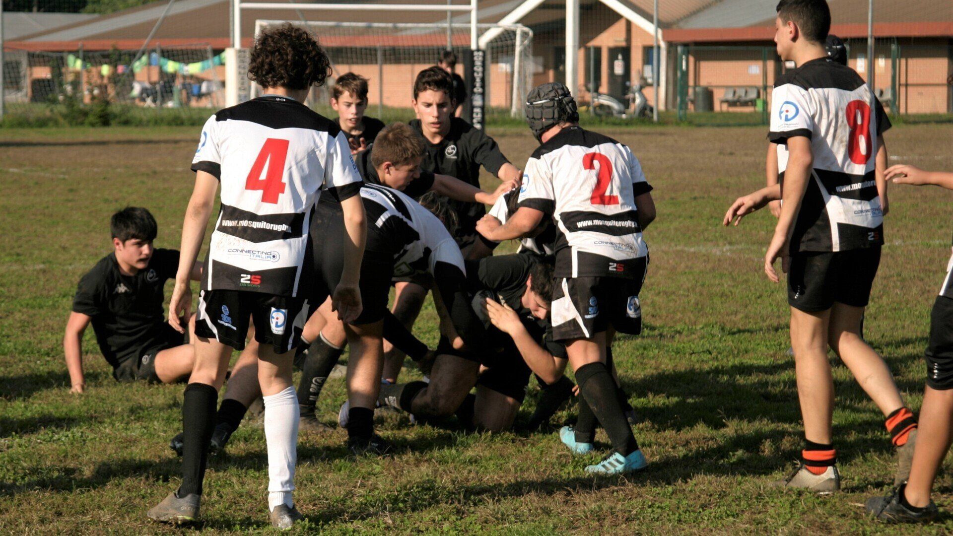 Un gruppo di ragazzi sta giocando una partita di rugby su un campo.