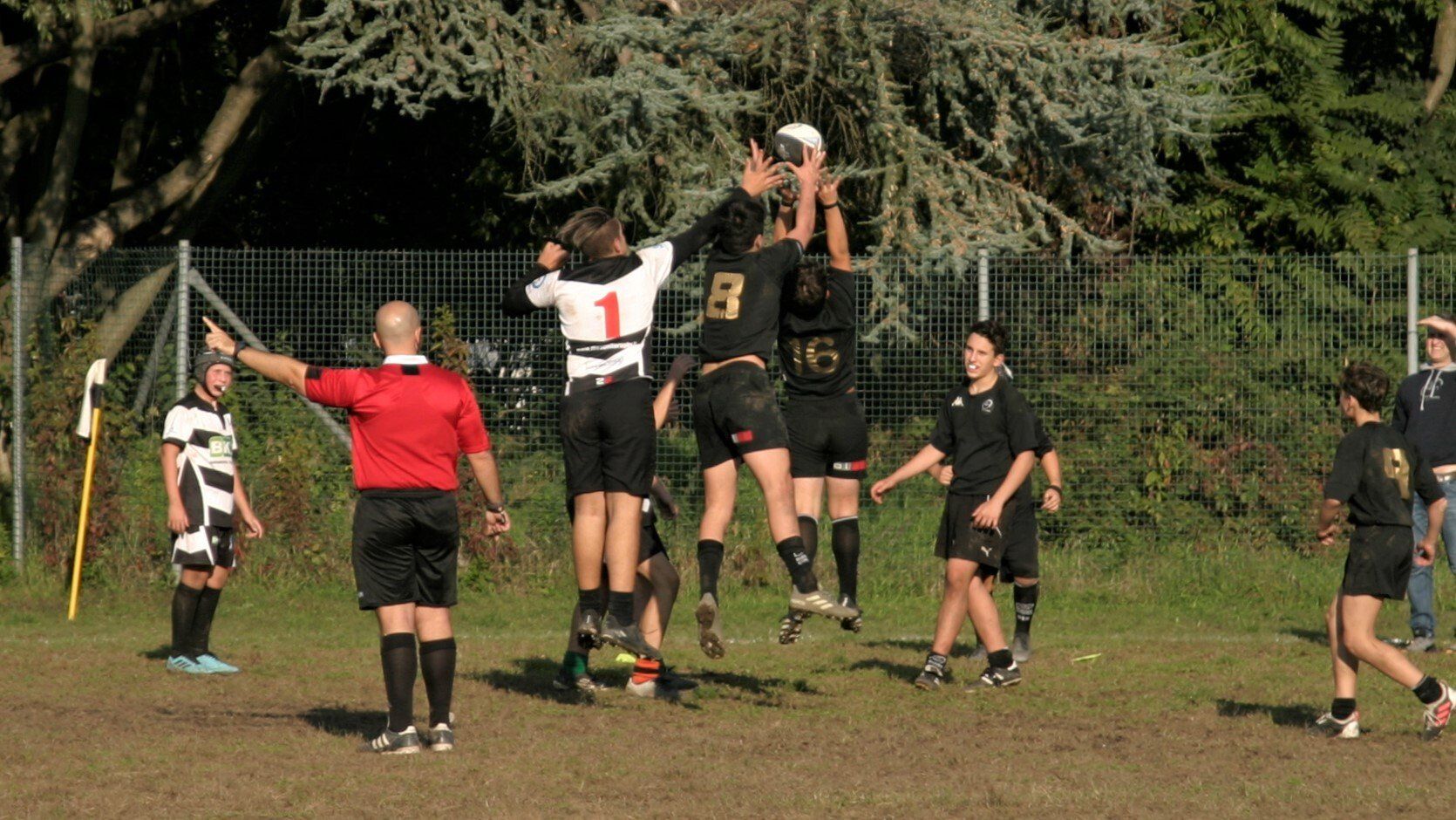 Un gruppo di giocatori di calcio salta in aria mentre un arbitro osserva