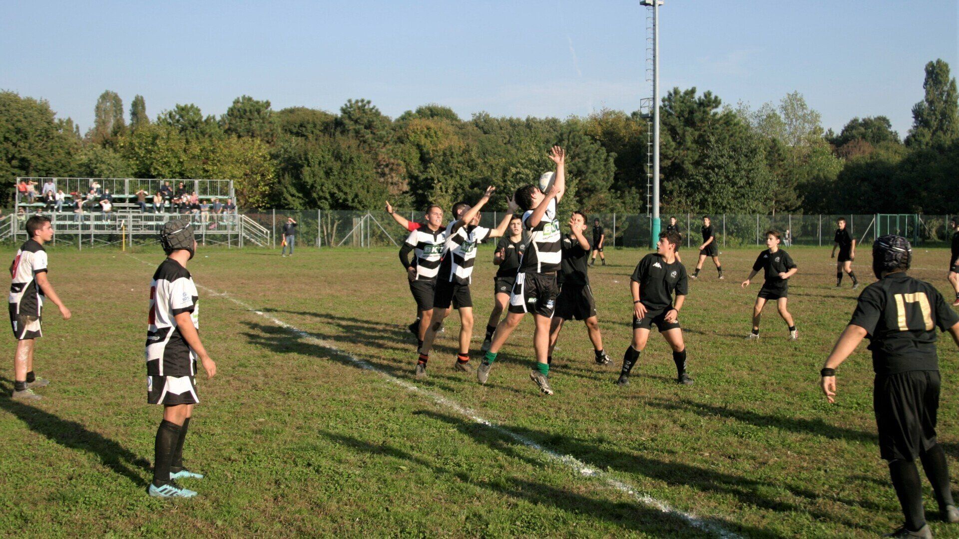Un gruppo di persone sta giocando una partita di rugby su un campo con un arbitro che indossa il numero 17