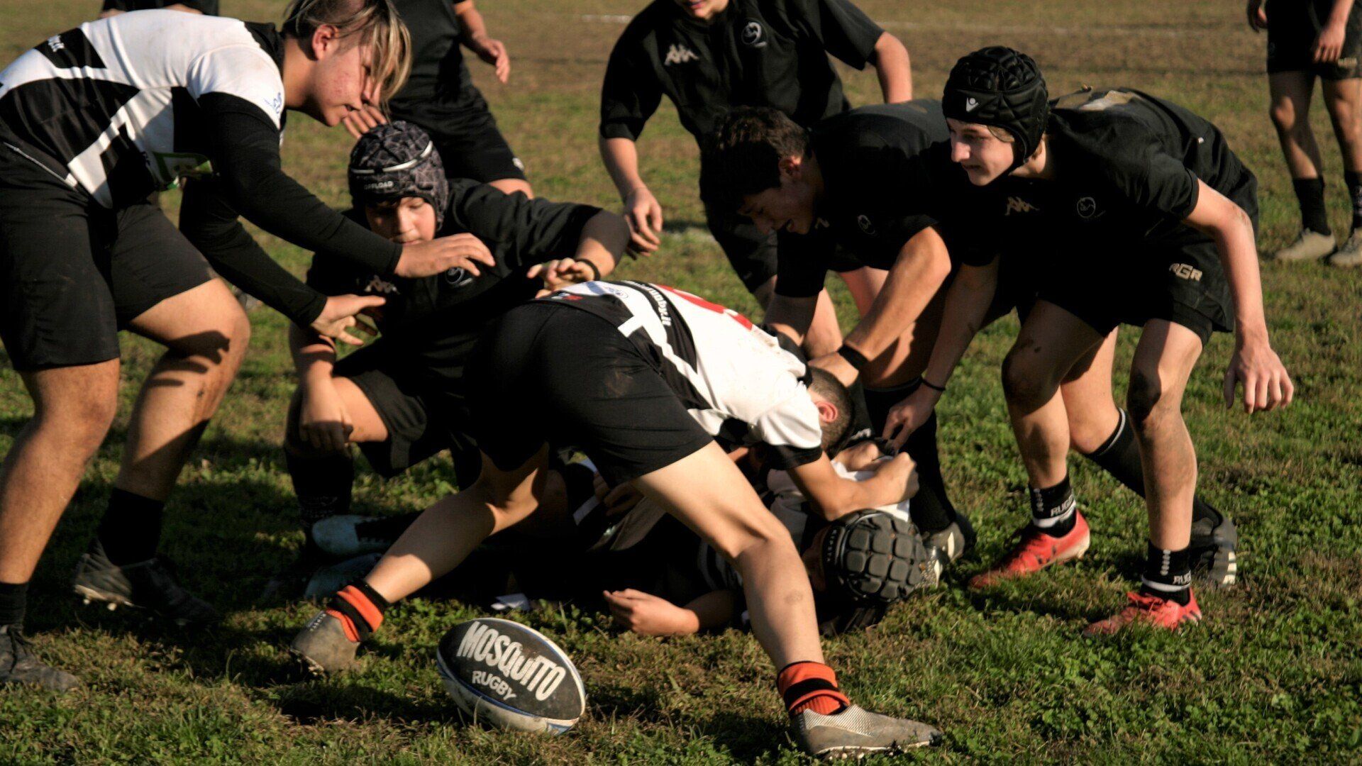 Un gruppo di giovani uomini sta giocando a rugby su un campo.
