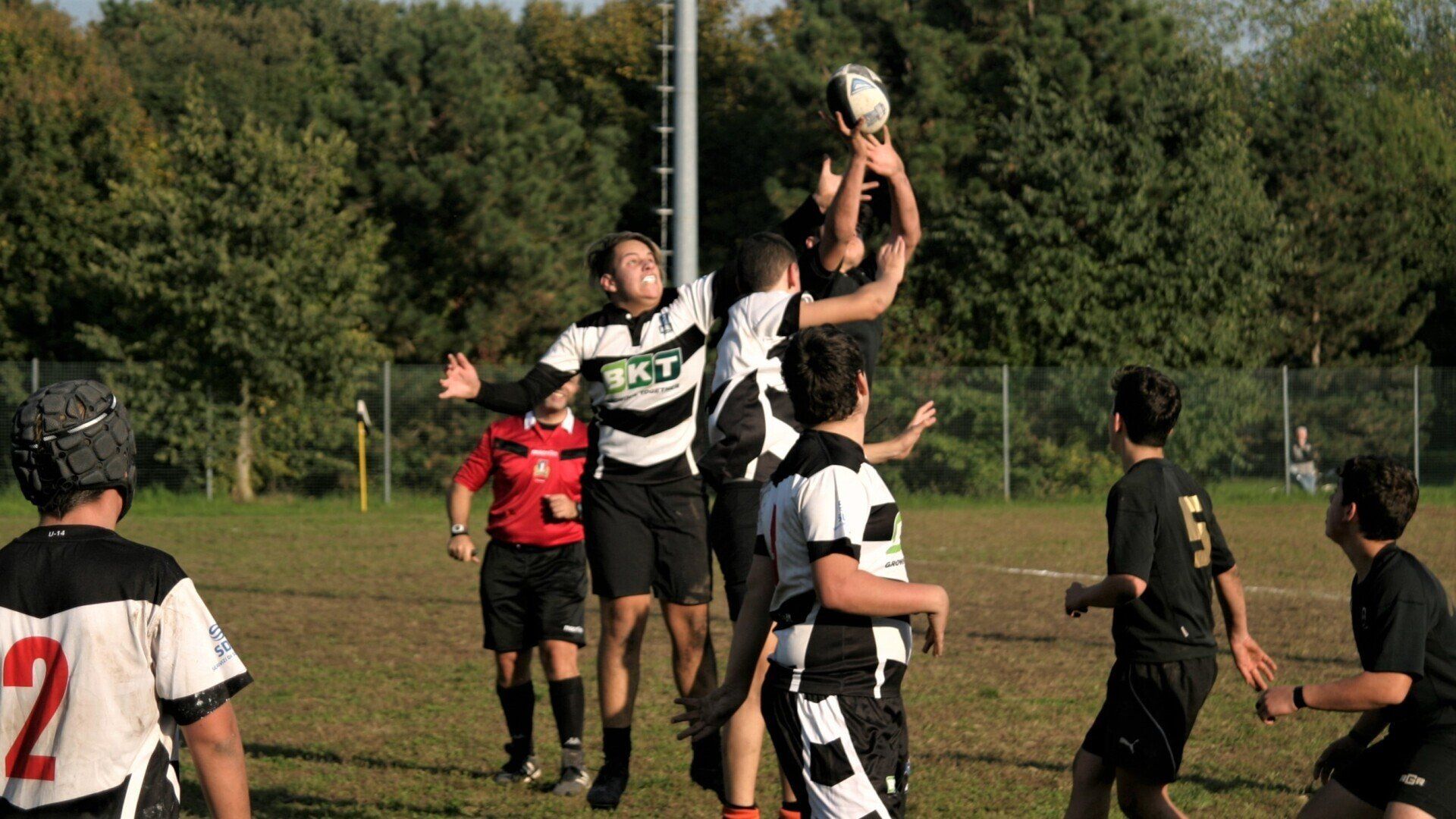 Un gruppo di giovani uomini sta giocando una partita di rugby su un campo.