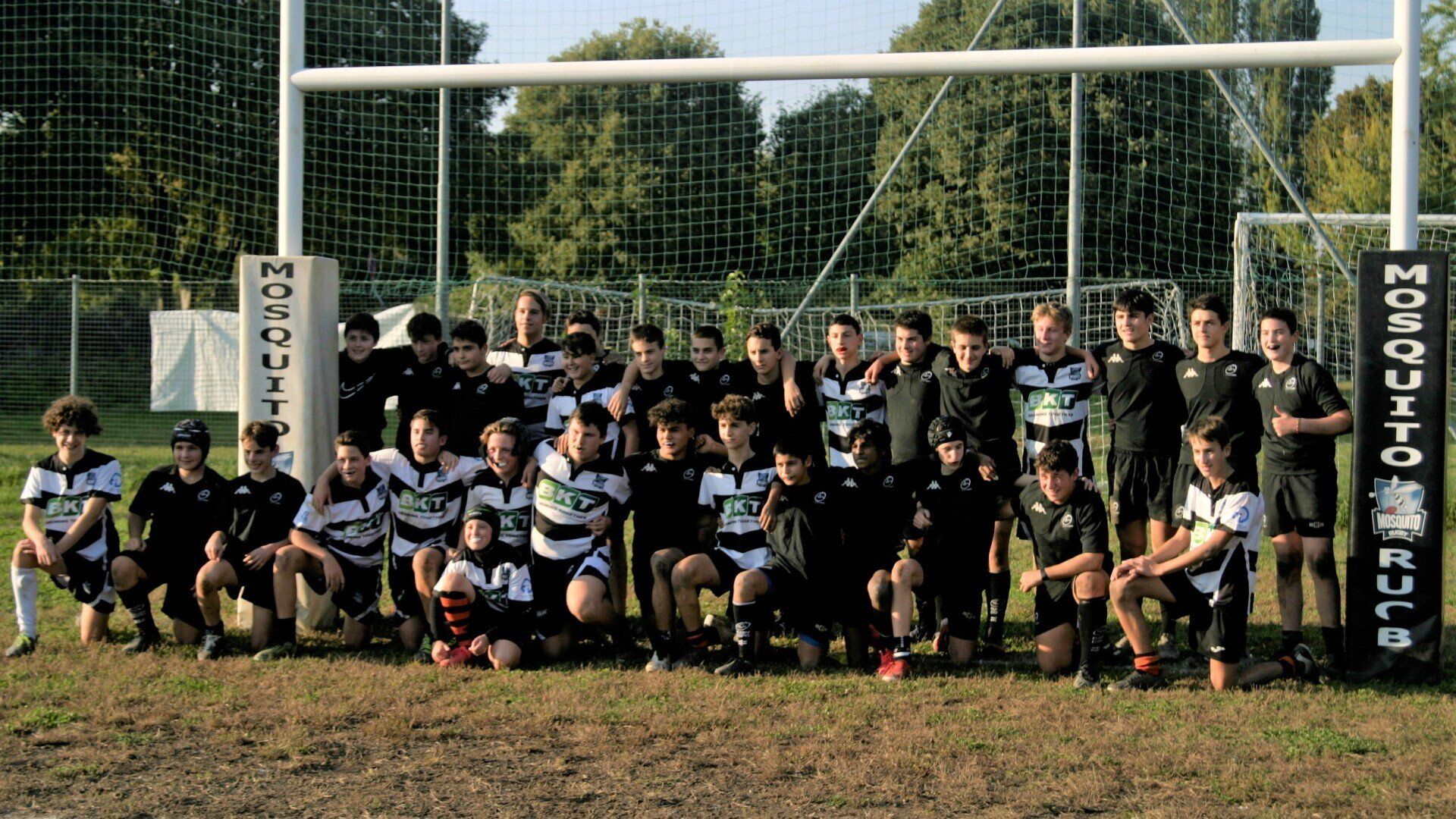 Un gruppo di giovani uomini posa per una foto davanti a una porta da rugby anti-zanzara.