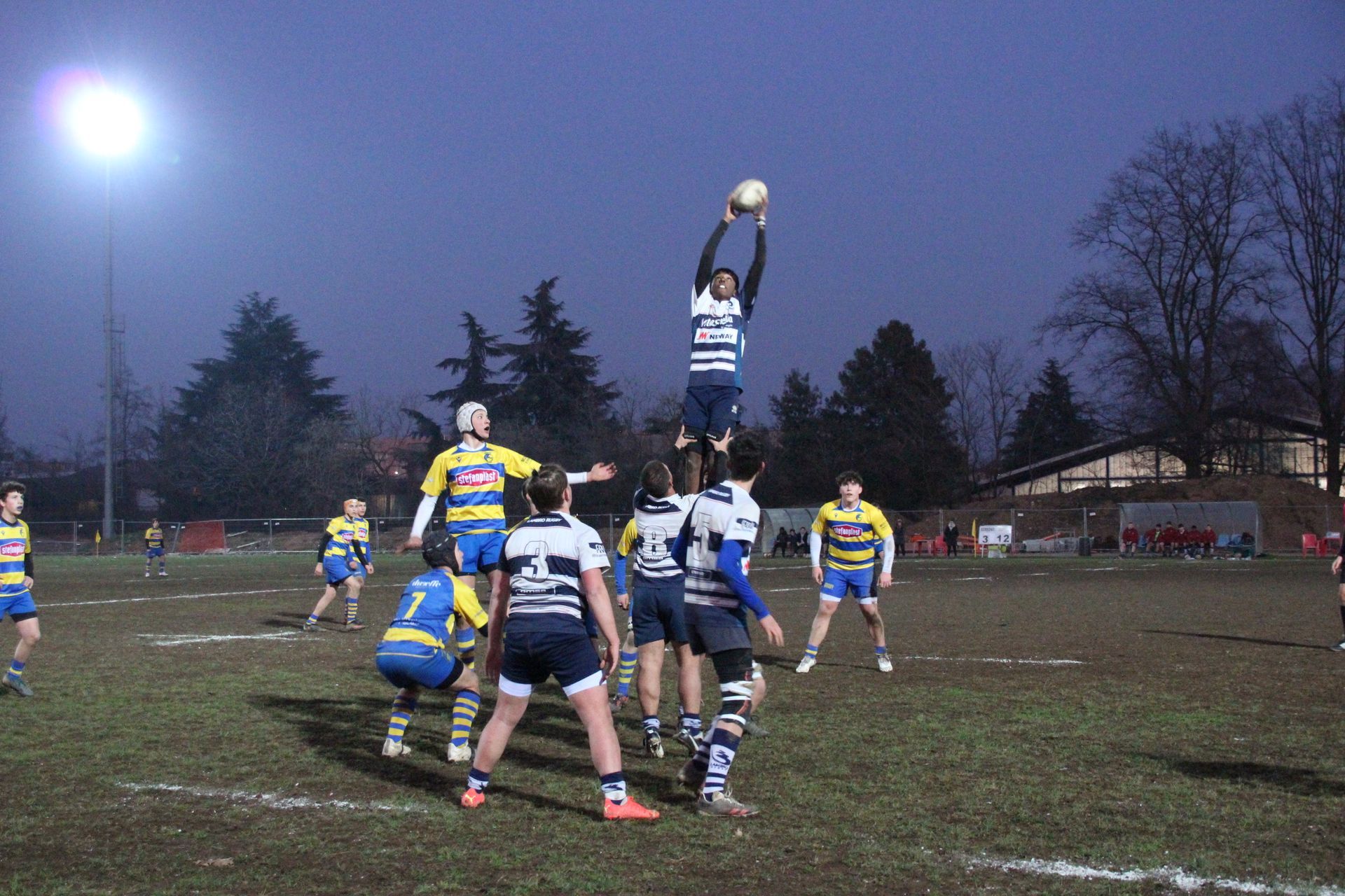 Un gruppo di giocatori di rugby sta giocando su un campo di notte