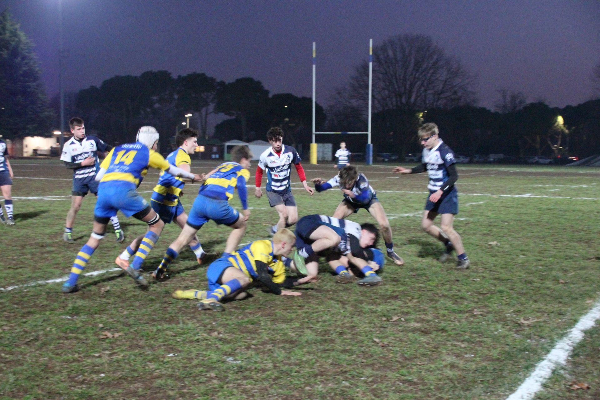 Un gruppo di giocatori di rugby sta giocando su un campo di notte.