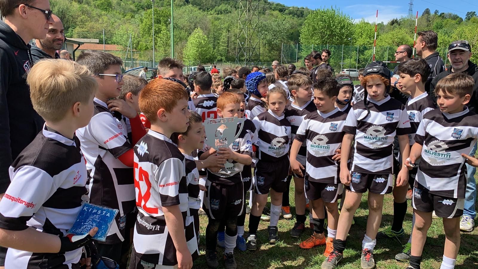 Un gruppo di ragazzi con indosso magliette a righe bianche e nere è in piedi in un campo.