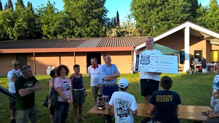 Un uomo tiene in mano un assegno di grandi dimensioni davanti a un gruppo di persone.