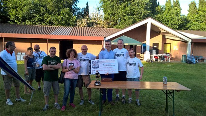 Un gruppo di persone in piedi davanti a una casa che tiene in mano un assegno di grandi dimensioni