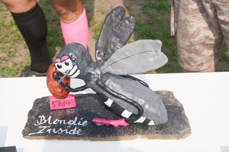 Una statua di una zanzara che mangia una salsiccia con la scritta 