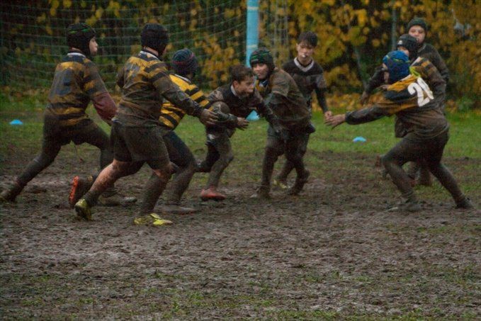 Un gruppo di ragazzi gioca a rugby su un campo fangoso.