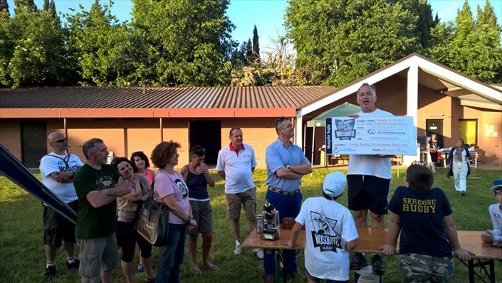 Un uomo tiene in mano un assegno di grandi dimensioni davanti a un gruppo di persone