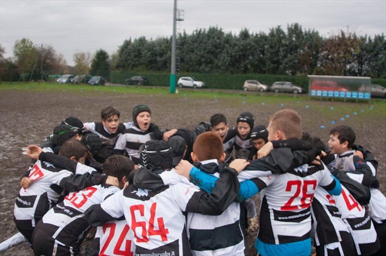 Un gruppo di ragazzi che indossano uniformi bianche e nere con i numeri 24 e 28 sulla schiena sono ammassati insieme.