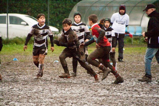 Un gruppo di ragazzi gioca a rugby su un campo fangoso.