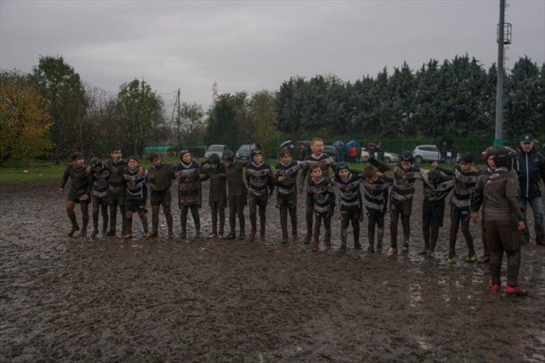 Un gruppo di bambini è in piedi in un campo fangoso.