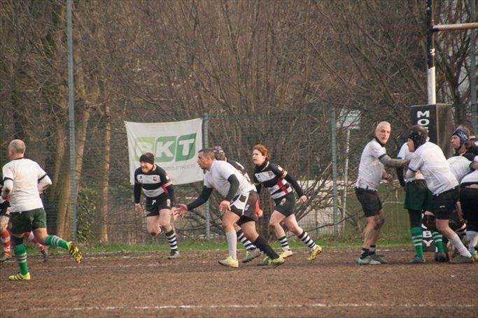 Un gruppo di uomini sta giocando a rugby su un campo con un cartello che dice pkt sullo sfondo.