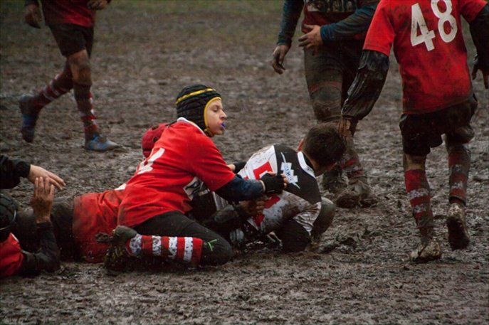 Un gruppo di ragazzi gioca a rugby nel fango.