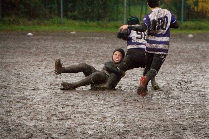 Un uomo è sdraiato a terra nel fango mentre gioca a rugby.