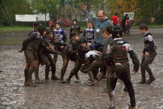 Un gruppo di ragazzi sta giocando a rugby in un campo fangoso.