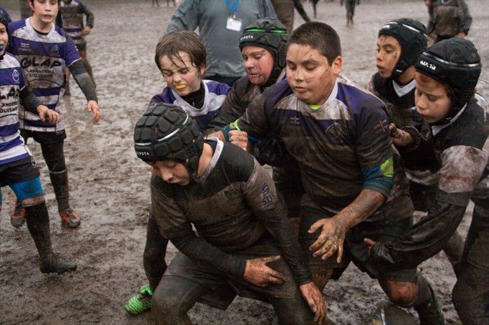 Un gruppo di ragazzi gioca a rugby nel fango.