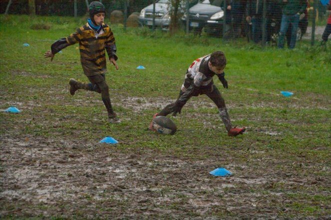 Due ragazzi stanno giocando a calcio in un campo fangoso.