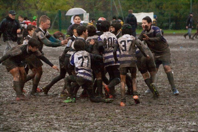 Un gruppo di ragazzi gioca a rugby su un campo fangoso.